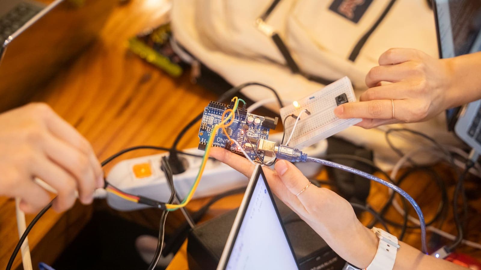 A team wiring a microcontroller and breadboard on a bench