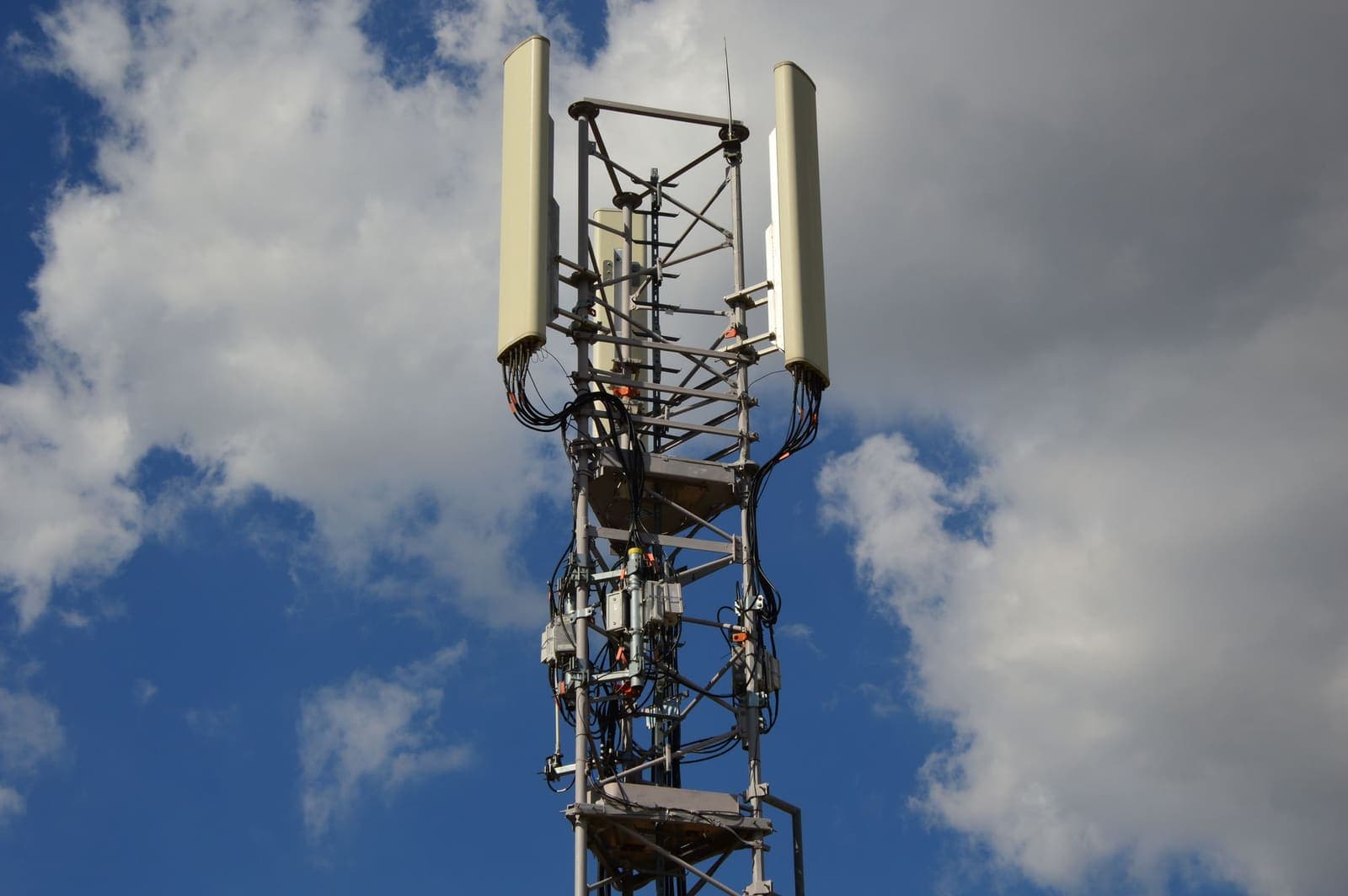 A modern cell tower with panel antennas against a blue sky