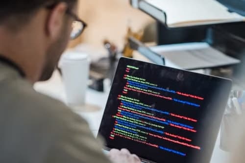 An engineer at a laptop, working through code at the desk