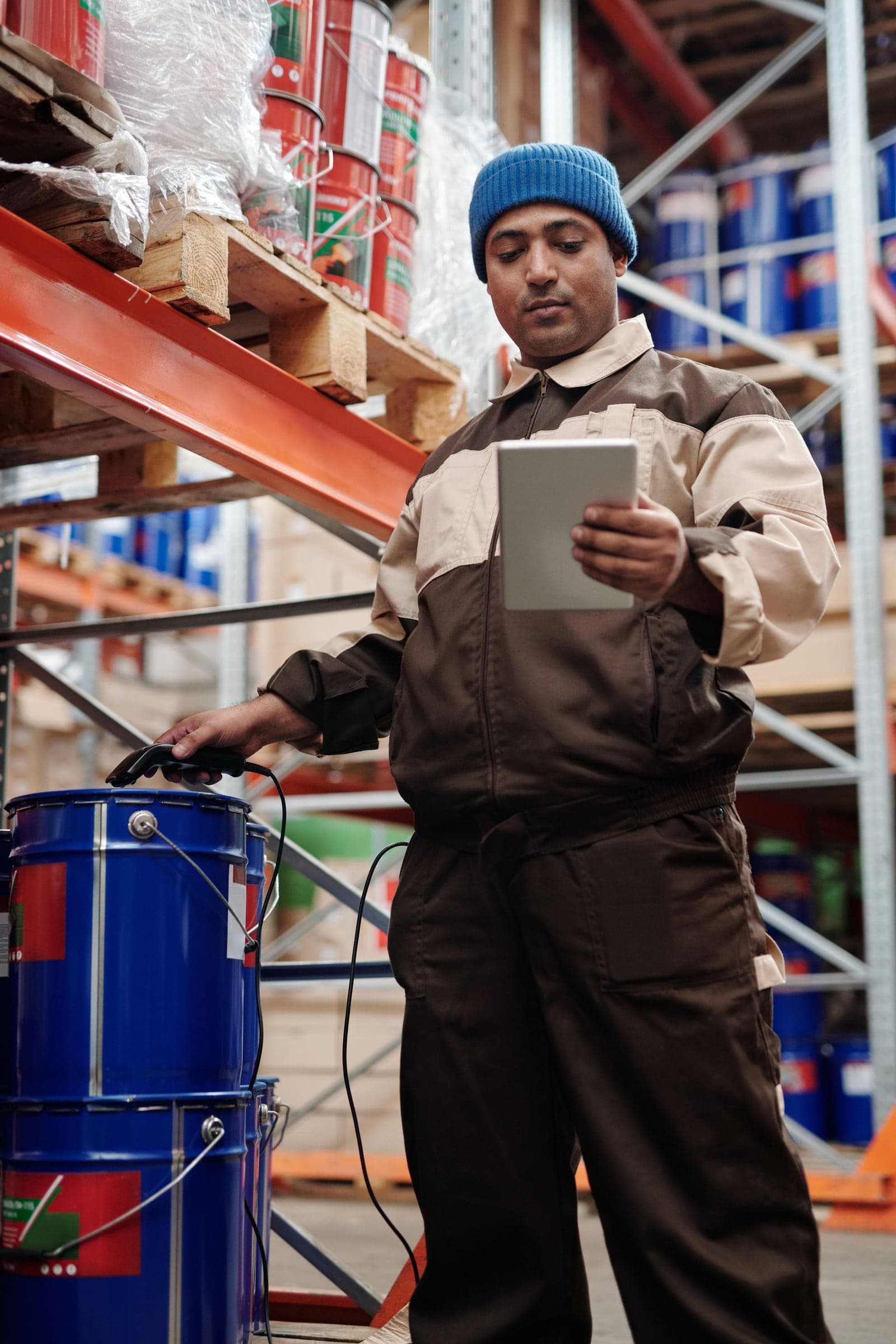 A warehouse worker with a tablet beside the racking